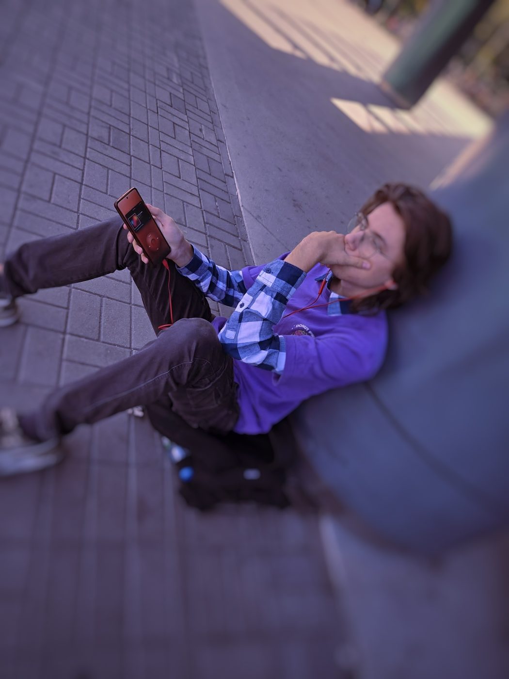 Leaning back against a wall with the player held out at arm's length.