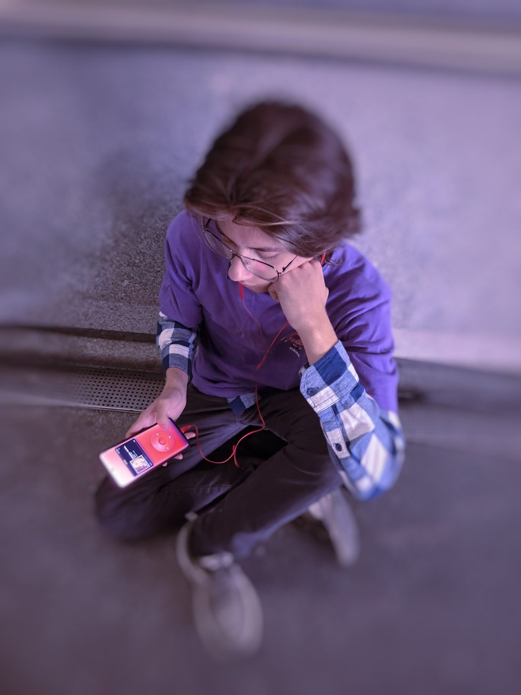 Sitting on a step, chin on one hand, the player held in the other.